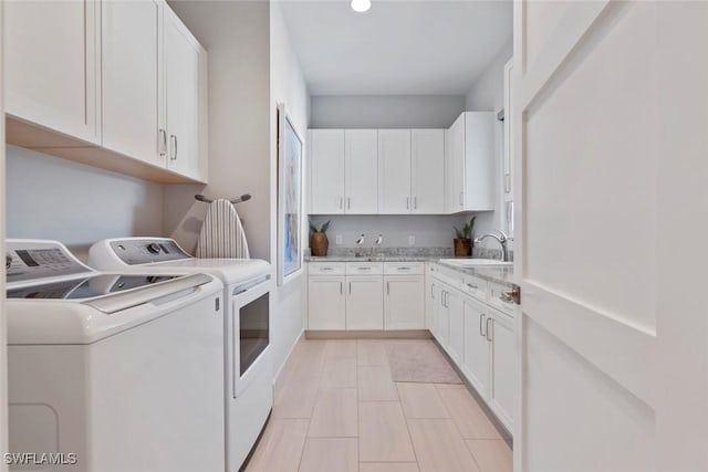 clothes washing area with washer and dryer, cabinets, and sink