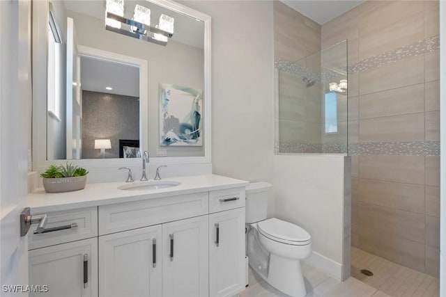 bathroom featuring a tile shower, tile patterned flooring, vanity, and toilet