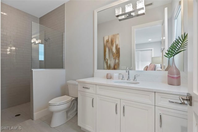 bathroom with tile patterned floors, vanity, toilet, and tiled shower