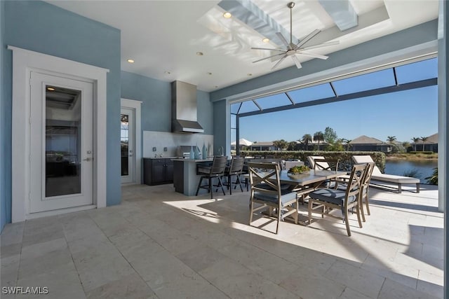 view of patio with a water view, ceiling fan, and exterior kitchen