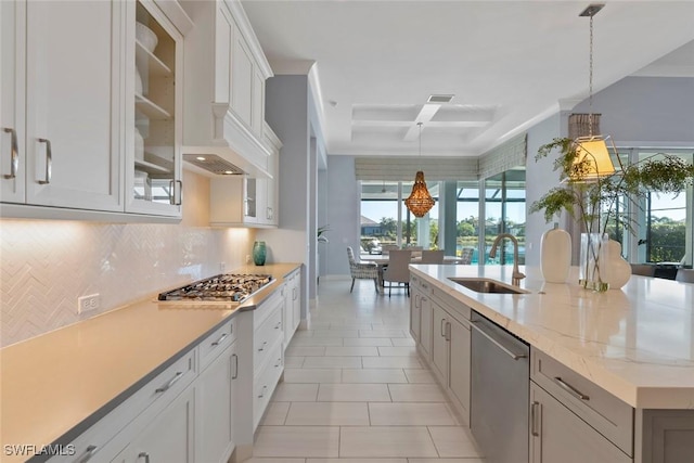 kitchen featuring appliances with stainless steel finishes, sink, white cabinets, hanging light fixtures, and an island with sink