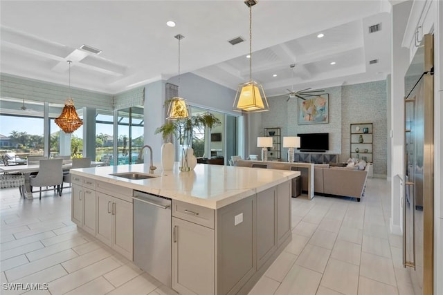 kitchen with stainless steel dishwasher, coffered ceiling, sink, a center island with sink, and hanging light fixtures