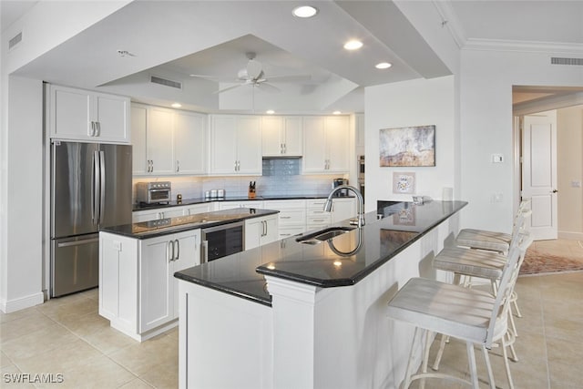 kitchen with stainless steel fridge, white cabinetry, and sink