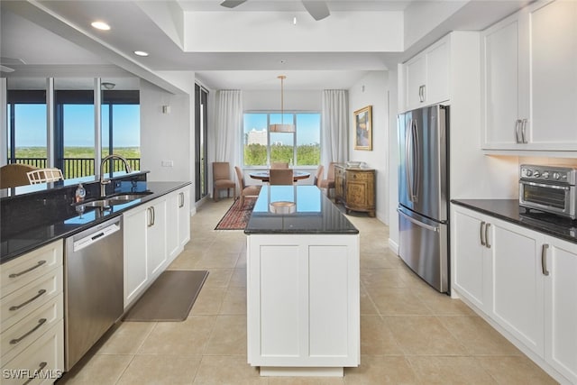 kitchen featuring a center island, sink, light tile patterned floors, appliances with stainless steel finishes, and white cabinetry