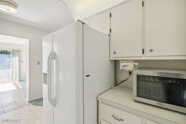 kitchen featuring a textured ceiling, white cabinetry, light tile patterned flooring, and white refrigerator with ice dispenser