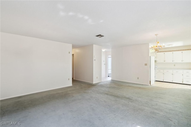 carpeted empty room featuring a chandelier