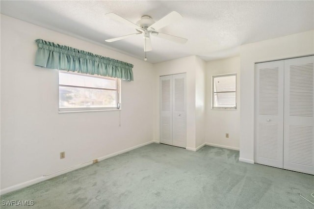 235 Thistle Ct, Lehigh Acres, FL 33936 - unfurnished bedroom with two closets, carpet, a textured ceiling, and ceiling fan