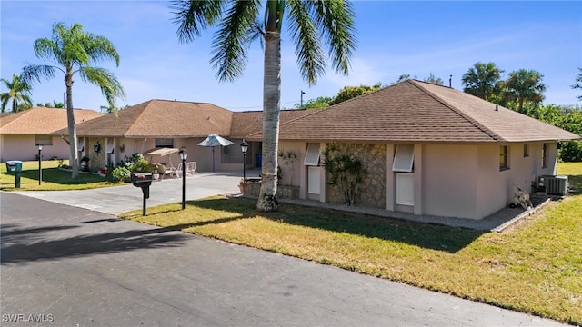 ranch-style home featuring central AC and a front lawn