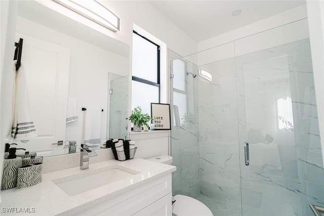 bathroom featuring vanity, a shower with shower door, and toilet