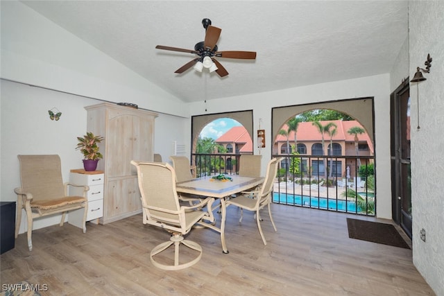 dining space featuring a textured ceiling, ceiling fan, lofted ceiling, and light wood-type flooring