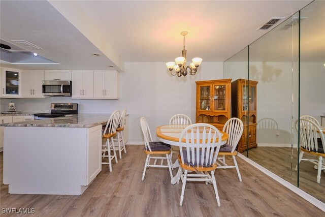 dining space featuring light hardwood / wood-style floors and an inviting chandelier