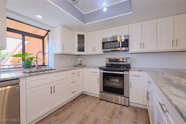 kitchen featuring sink, stainless steel appliances, light stone counters, light hardwood / wood-style floors, and white cabinets