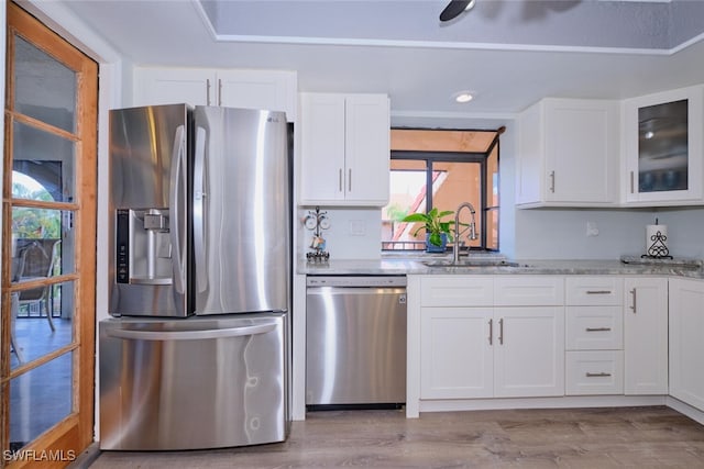 kitchen featuring white cabinetry, sink, stainless steel appliances, and light stone counters