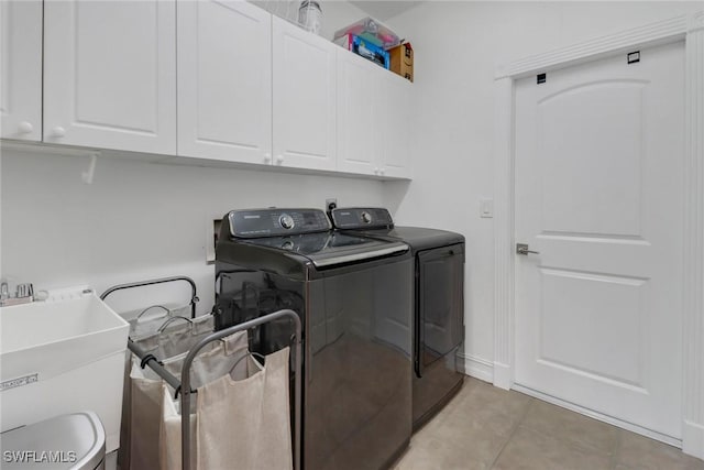 clothes washing area with light tile patterned flooring, cabinets, sink, and washing machine and clothes dryer