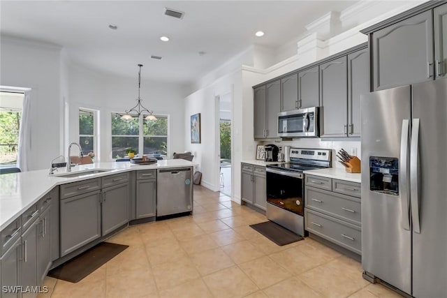 kitchen with sink, crown molding, gray cabinets, decorative light fixtures, and stainless steel appliances