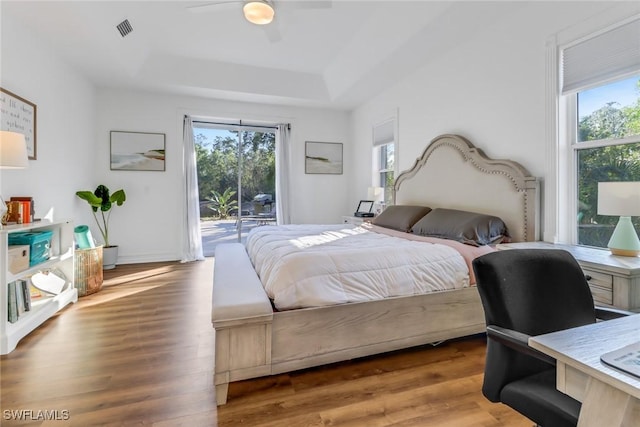 bedroom featuring hardwood / wood-style floors, ceiling fan, a raised ceiling, and access to outside