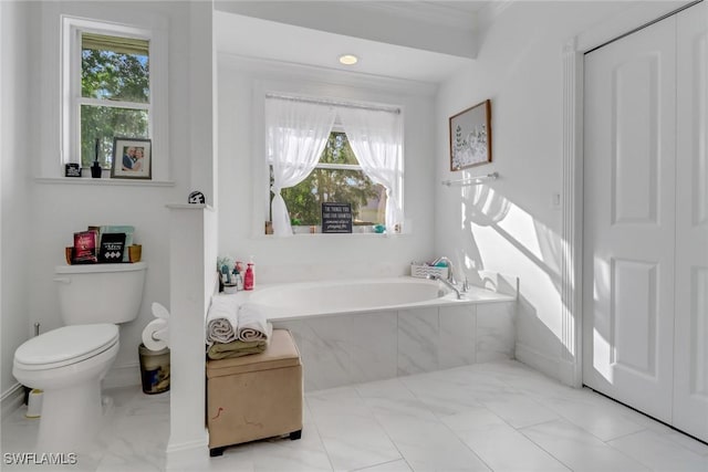 bathroom with tiled tub, ornamental molding, and toilet