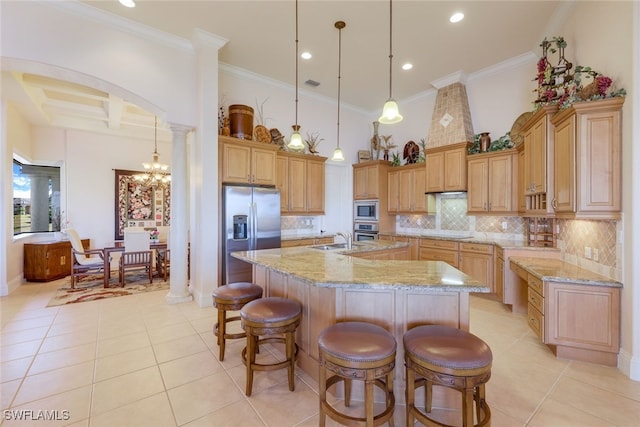 kitchen featuring stainless steel appliances, ornate columns, a kitchen island with sink, and crown molding