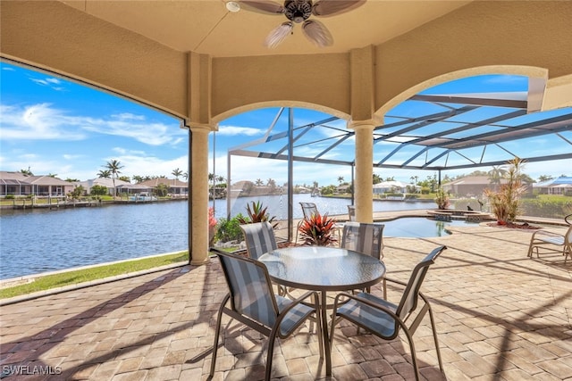 view of patio with a water view, glass enclosure, and ceiling fan