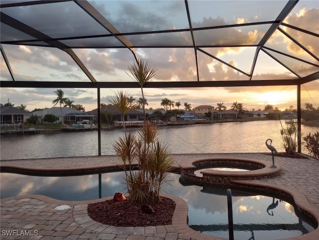 exterior space with a lanai, an in ground hot tub, and a water view