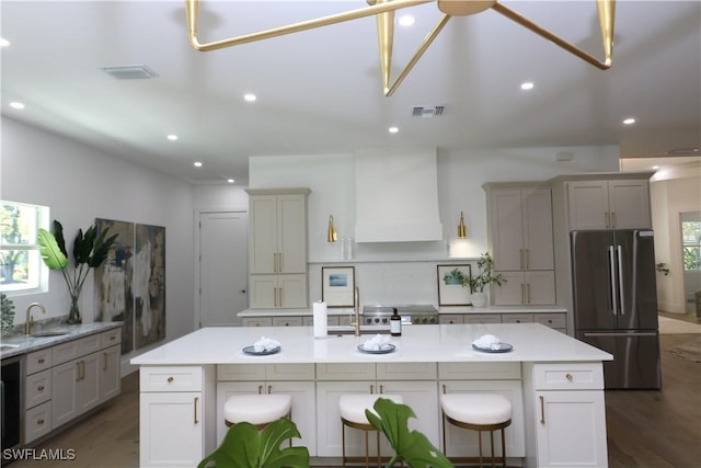 kitchen with light countertops, dark wood-type flooring, custom exhaust hood, and freestanding refrigerator