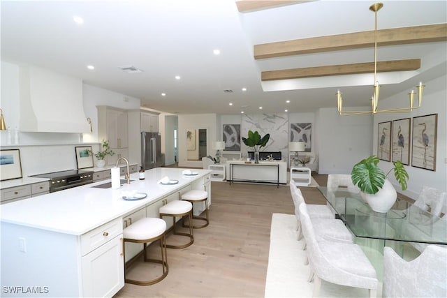 kitchen with light wood finished floors, high end fridge, recessed lighting, a sink, and premium range hood