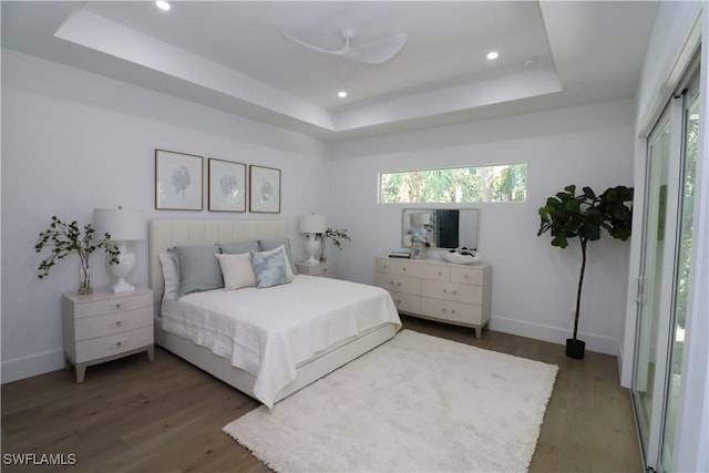 bedroom featuring wood finished floors, recessed lighting, a raised ceiling, and baseboards