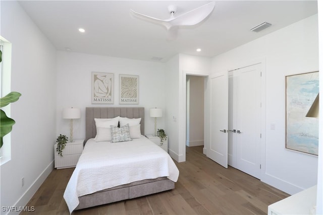 bedroom with baseboards, wood finished floors, visible vents, and recessed lighting