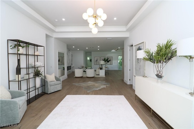 entrance foyer with a tray ceiling, recessed lighting, wood finished floors, a chandelier, and baseboards