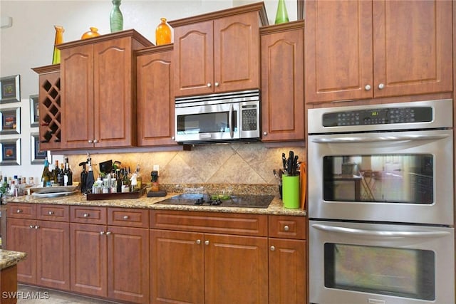 kitchen featuring stainless steel appliances, light stone counters, and tasteful backsplash