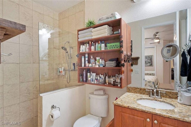 bathroom with a tile shower, ceiling fan, vanity, and toilet