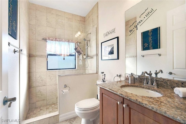 bathroom with tile patterned flooring, toilet, vanity, and tiled shower