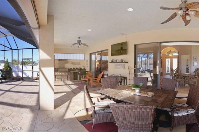 view of patio / terrace with glass enclosure, ceiling fan, and an outdoor kitchen