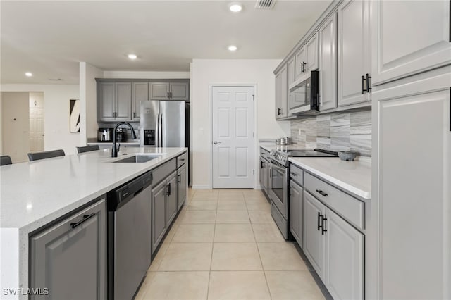 kitchen featuring decorative backsplash, gray cabinetry, stainless steel appliances, sink, and light tile patterned flooring