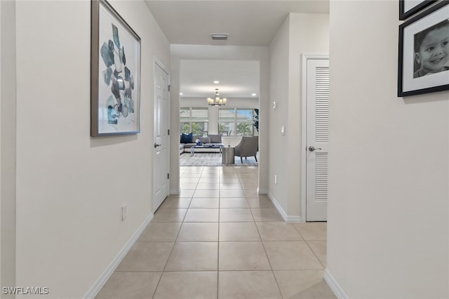 corridor featuring light tile patterned floors and an inviting chandelier