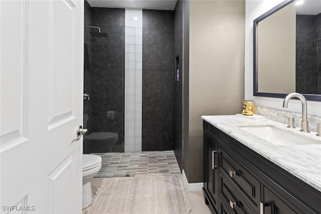 bathroom with tile patterned floors, vanity, toilet, and tiled shower