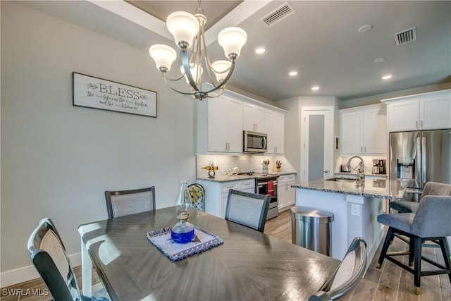 dining area featuring a chandelier, light wood-type flooring, and sink