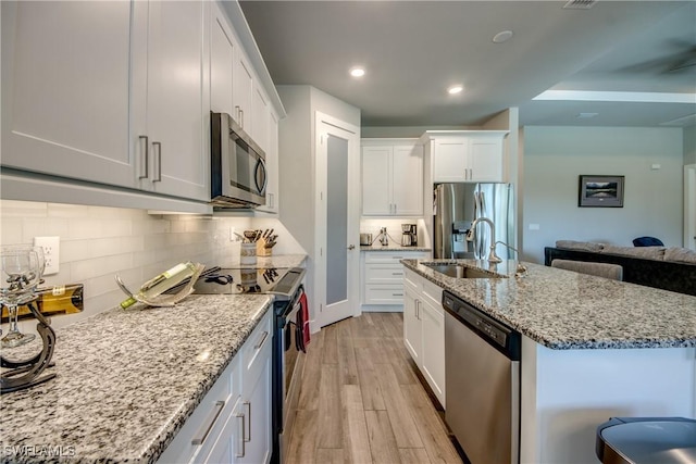 kitchen with sink, decorative backsplash, light hardwood / wood-style floors, white cabinetry, and stainless steel appliances