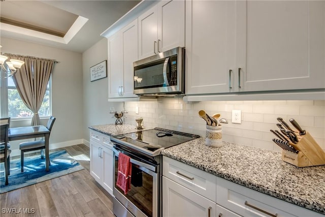 kitchen featuring light stone countertops, stainless steel appliances, light hardwood / wood-style floors, decorative backsplash, and white cabinets