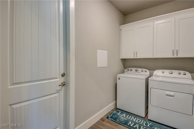 washroom with washer and dryer, light hardwood / wood-style flooring, and cabinets