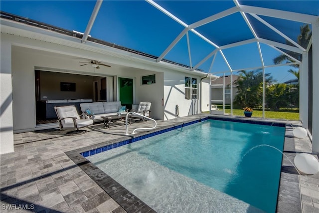 view of swimming pool with glass enclosure, ceiling fan, a patio, and an outdoor living space