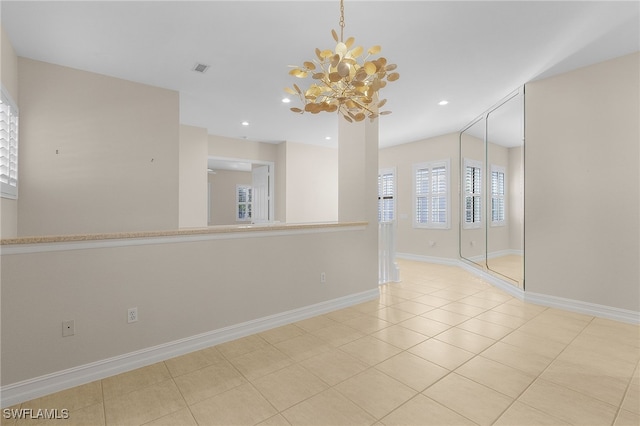 spare room featuring light tile patterned floors and a chandelier