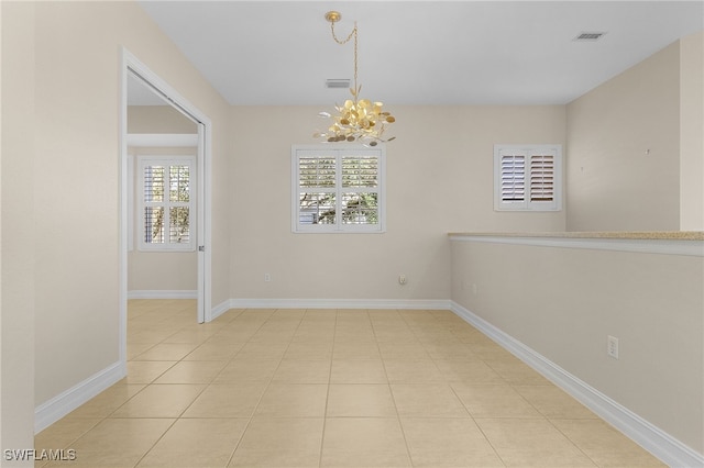 tiled spare room with a chandelier