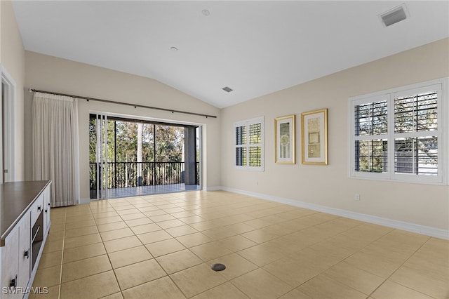 tiled empty room featuring vaulted ceiling