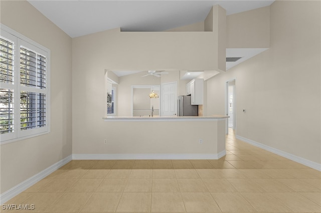 interior space featuring ceiling fan, light tile patterned floors, and vaulted ceiling