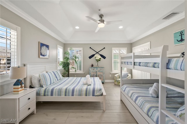 bedroom featuring ceiling fan, light wood-type flooring, ornamental molding, and a tray ceiling