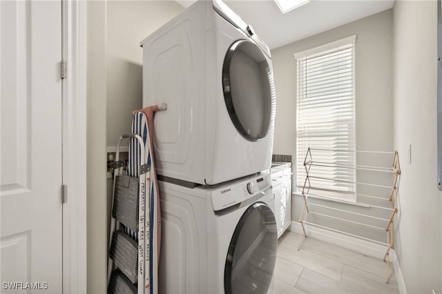 laundry area with cabinets and stacked washing maching and dryer