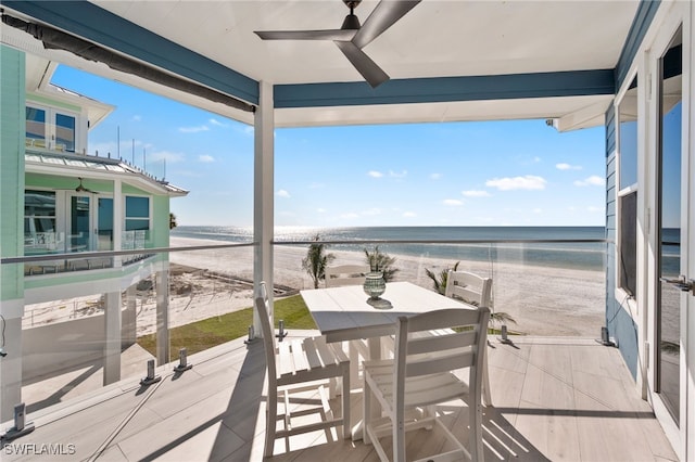 balcony featuring ceiling fan, a water view, and a beach view