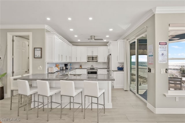 kitchen with appliances with stainless steel finishes, white cabinetry, and a breakfast bar area