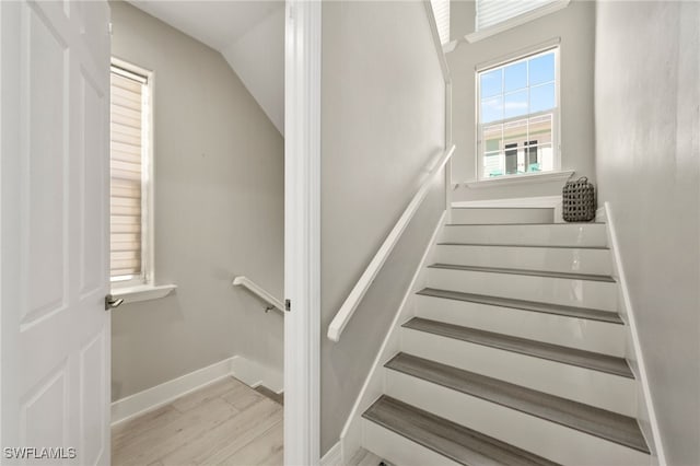 stairway featuring hardwood / wood-style flooring and lofted ceiling